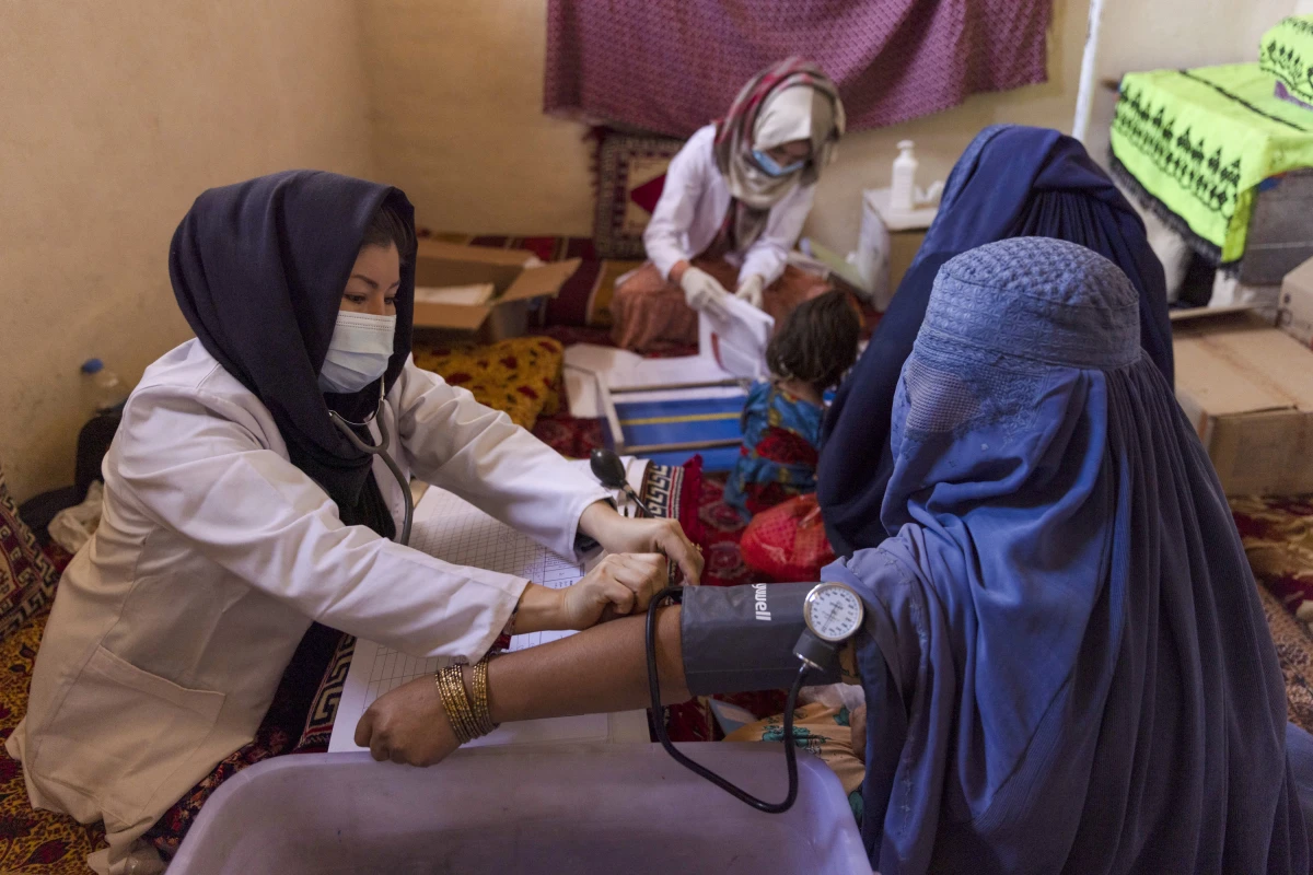 A midwife assesses a pregnant woman at a mobile health clinic in Afghanistan. In the wake of the freeze of USAID, some 200 clinics in the country have had to close.  Midwives told NPR that it's now more difficult for pregnant women, especially in remote areas, to get medical care in case of a crisis.