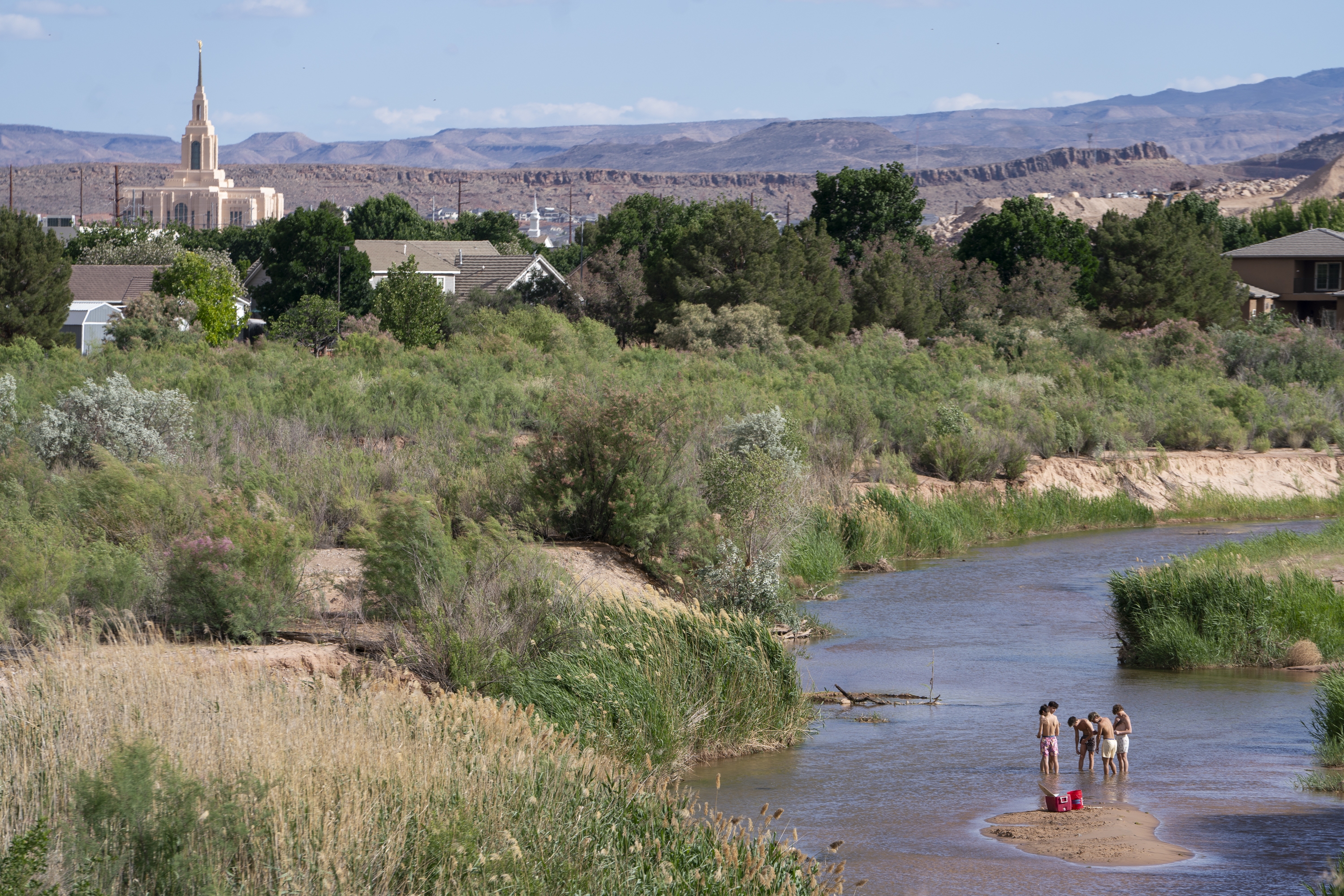 People wade in the shallow waters of the Virgin River in St. George, Utah. The river provides the desert community with water, but climate change and a growing population threaten that supply. Local leaders are looking toward recycled sewage as a solution. (NPR)