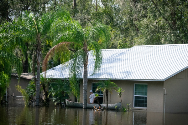 In a flooded Valrico neighborhood a man waits outside of a home after paddle two others, who entered through the window, up to it.