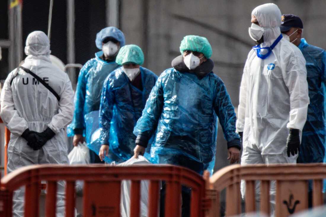 Passengers carry their belongings in plastic bags after being evacuated from the MV Hondius after docking in the Granadilla Port on May 10, 2026 in Tenerife, part of the Canary Islands, Spain.