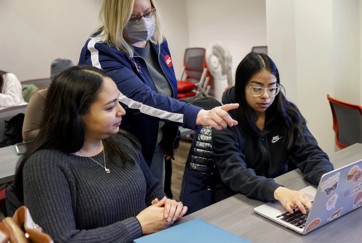 Ashton Spatz, center, a financial aid adviser with the University of Illinois at Chicago, assists Jessena Sanchez, left, and her daughter, Leslie Delve, a sophomore at UIC, during a FAFSA workshop in February 2024.