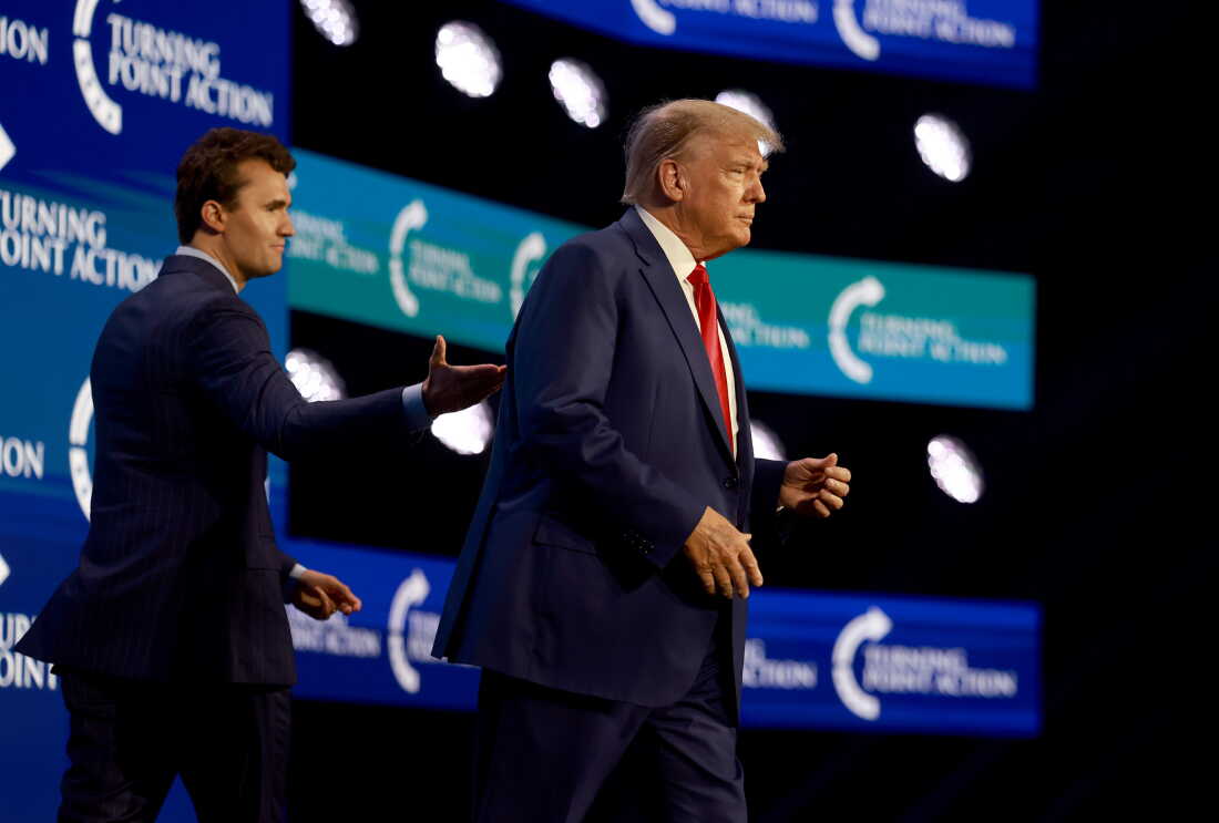 Donald Trump, on the right side of the frame, walks onstage after being introduced by Charlie Kirk, on the left side of the frame, at the Turning Point Action conference on July 15, 2023, in West Palm Beach, Florida.