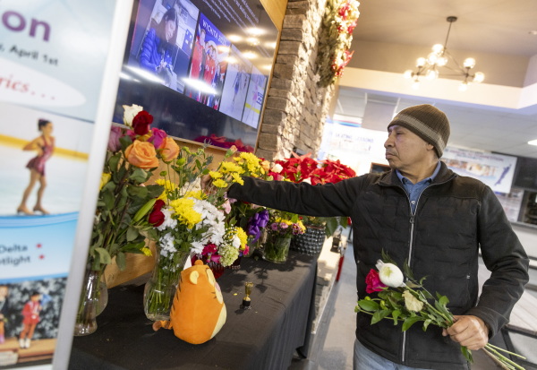 Fairfax Ice Arena employee Isaias Rosa places flowers to honor the victims who were killed in the plane crash on Wednesday night. More than a dozen of the passengers were figure skaters, coaches or family members.