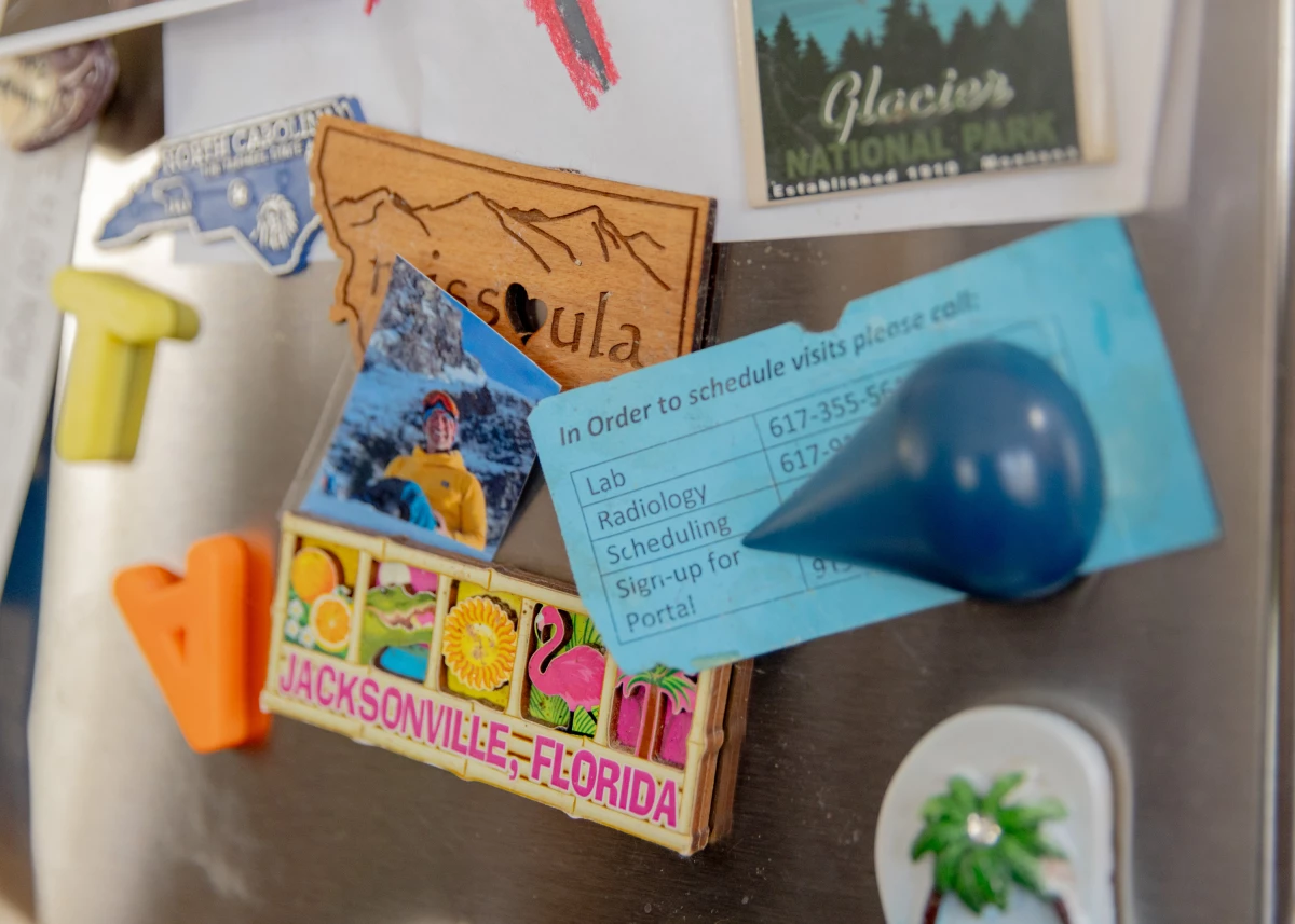 A scheduling card for medical appointments appears among vacation magnets on Logan's family fridge.