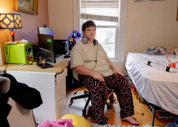 Logan sits in his room in his family’s home in Newton, Mass. Logan enjoys physics and computers. An avid gamer, he built the PC on the desk behind him.