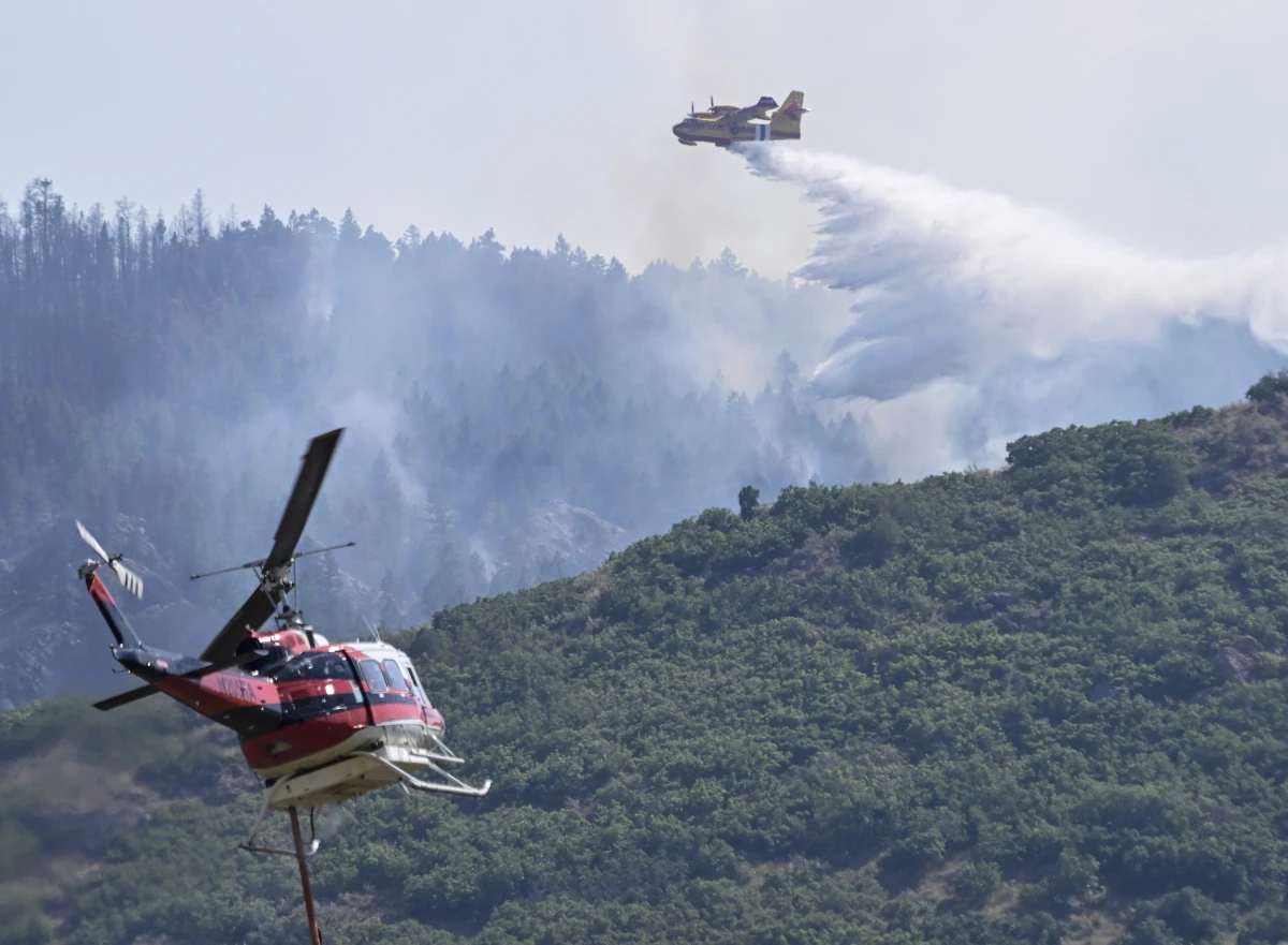 A CL 415 scooper, top, drops water on the Quarry Fire as a Firehawk helicopter maneuvers for a water drop Thursday, Aug. 1, 2024, southwest of Littleton, Colo.