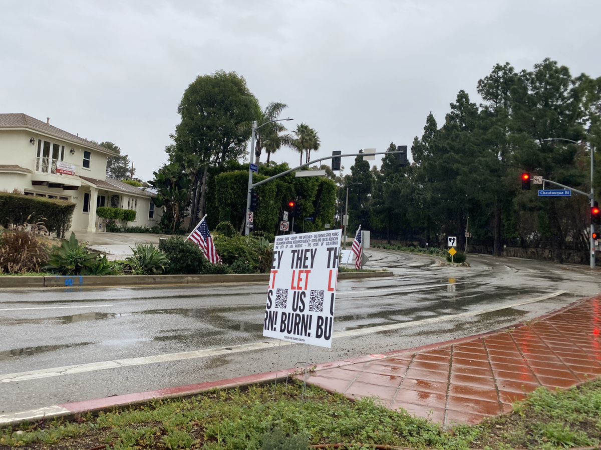 A sign in the Palisades marks a protest a year after the LA fires. There's a widespread lack of trust with state and local agencies amongst many fire survivors.