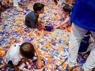 Young New York Knicks fans play with ticker tape during the parade celebrating the Knicks' 2026 NBA Championship win.