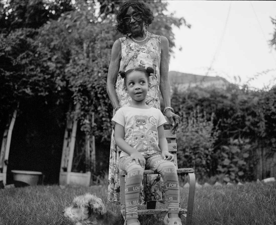 Stevens’ niece Sage Belgrave, 5, sits in front of her great-great-grandmother Georgia Monroe, 92, and the family dog, Benji, in the backyard of Monroe’s home in Cambria Heights. Together, they embody five living generations.