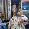 Amtrak employees assist a woman onto a train.