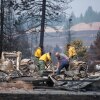 Firefighters and residents dig through debris on Tuesday after a wildfire destroyed homes in a neighborhood in Spokane, Wash.