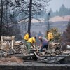 Firefighters and residents dig through debris on Tuesday after a wildfire destroyed homes in a neighborhood in Spokane, Wash.