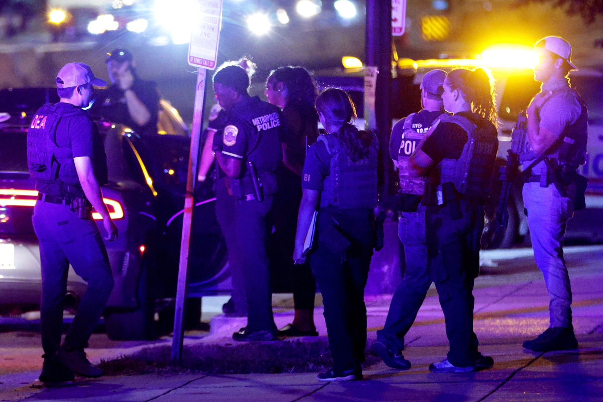 Federal and local law enforcement officers investigate a suspect's vehicle on South Capitol Street on Monday in Washington, D.C. President Trump announced a federal takeover of D.C. police and mobilization of the National Guard.