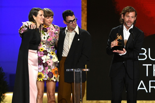 Laura Sisk (left), Taylor Swift, Jack Antonoff and Aaron Dessner accept the Album of the Year award for Folklore at the Grammy Awards in 2021. Dessner is speaking at the microphone and holding the award.
