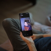 Debbie Willson holds her smartphone, which is displaying a photo of her son, Adam Willson, who died at age 27 in 2024. Adam is wearing a T-shirt that says "Jason Lives," with an image of the horror movie character Jason holding an axe above his head.