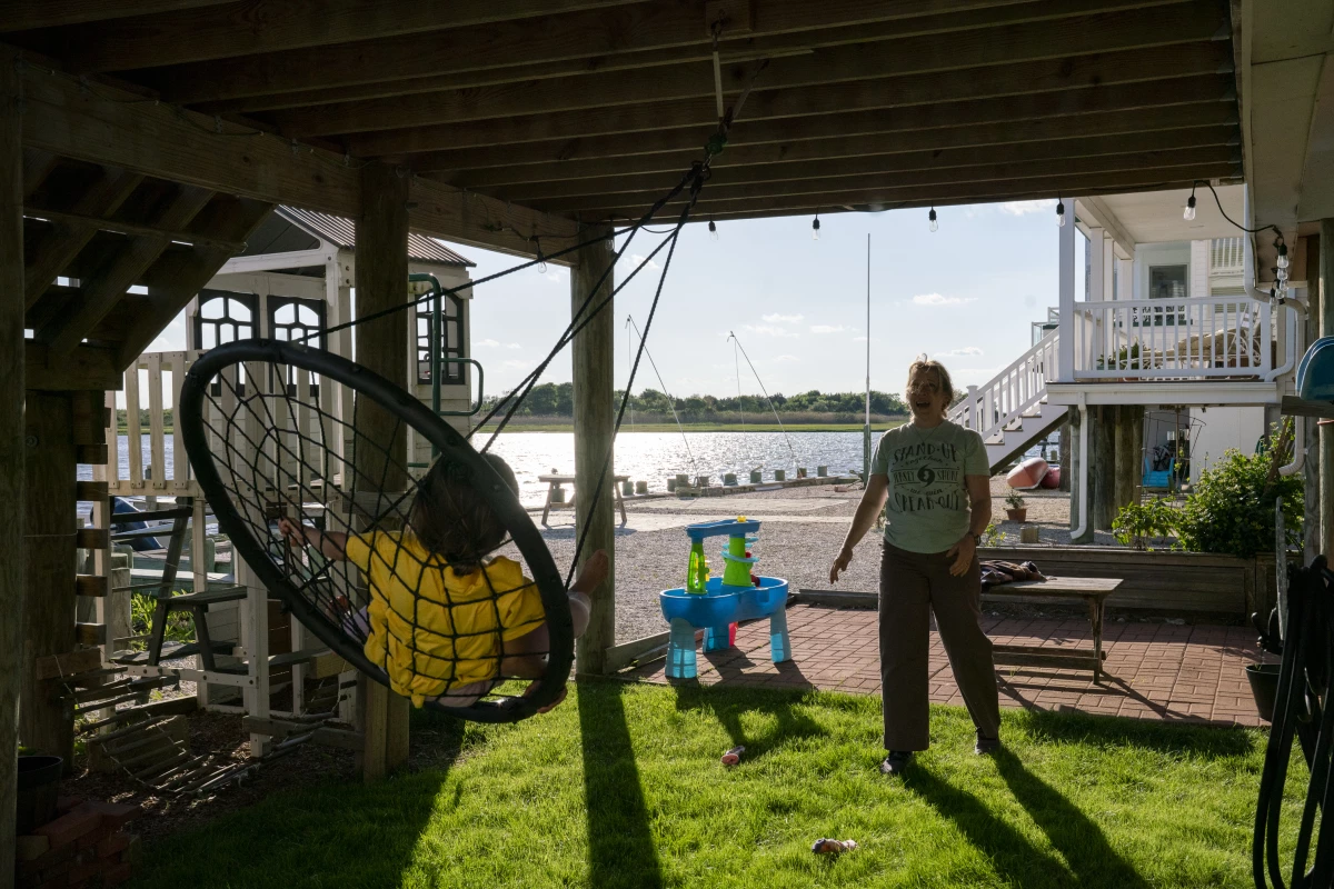 Devecka-Rinear pushes her daughter on a swing underneath the now-elevated home where she visited her grandmother while growing up. She doesn't want to leave the small island where she lives. 'For me, being here is still being with my grandmother,' she says.