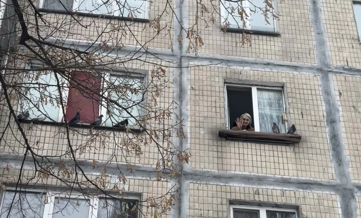 Nelia Stepanivna Thomashevska, an 80-year-old resident of Kyiv, Ukraine, waves from her kitchen window.