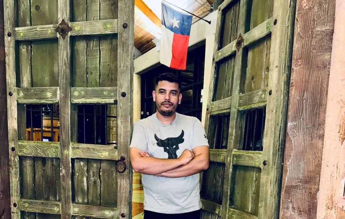 A man stands in a doorway with arms crossed.