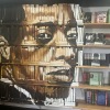 On the left side of this photo, James Baldwin's face is painted on a decorative bookcase inside the Baldwin & Co. bookstore in New Orleans. On the right are books arranged on rows of bookshelves.