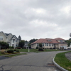 A view from the road shows large, multistory homes with grassy yards.