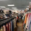 Racks of clothes and shoes inside a thrift store.