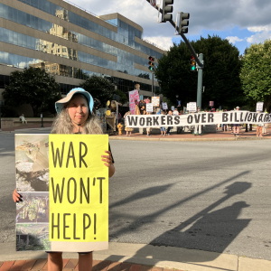 Demonstrator Lola La Fey holds a sign showing damage her home sustained from Hurricane Helene as she stands near Pack Square in Asheville on Friday, August 28, 2026.
