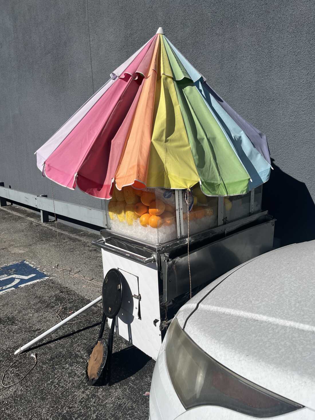 Jesús González's fruit cart is packed up, with the rainbow umbrellas collapsed on top of it.