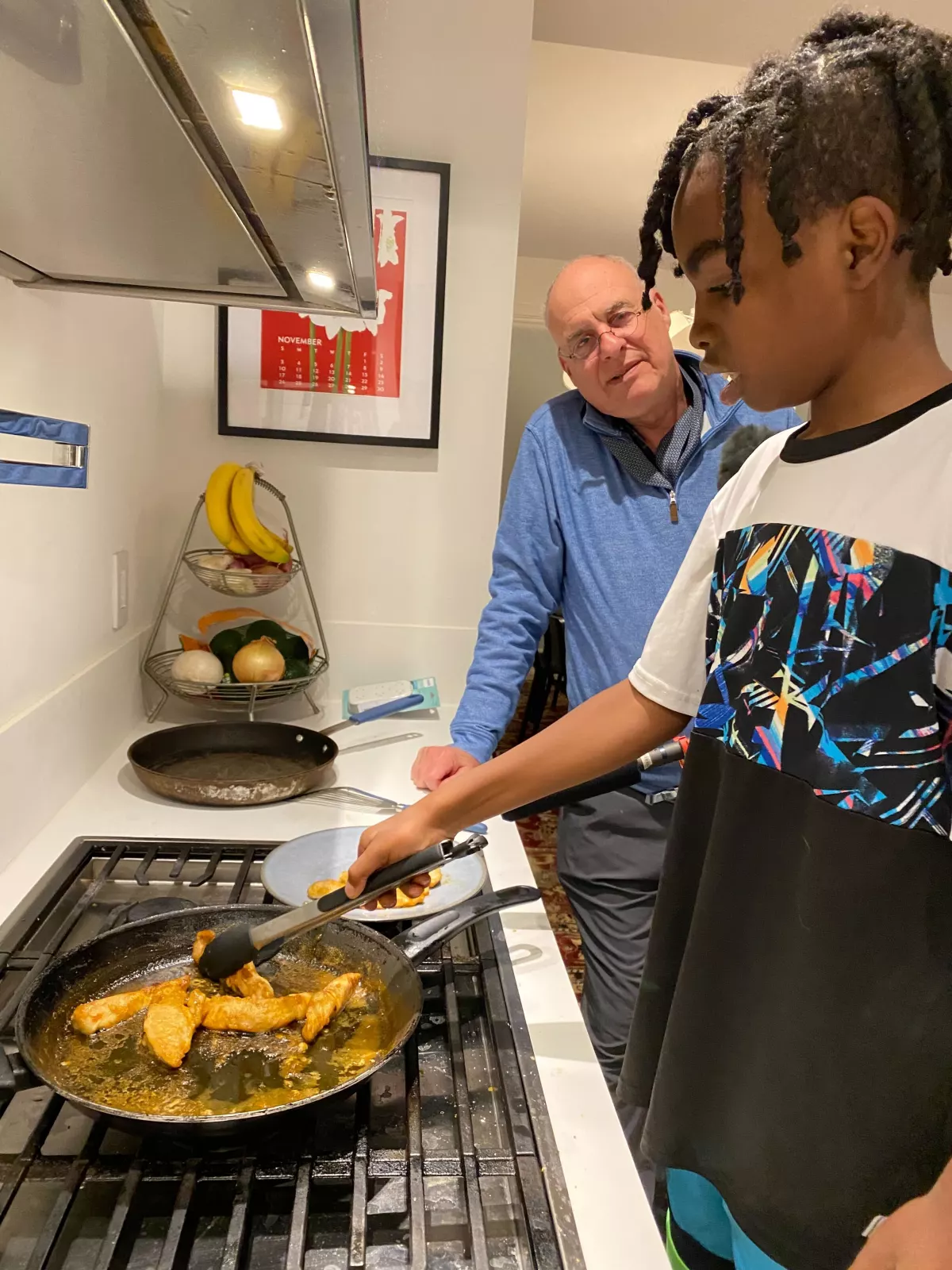 Ayesha Rascoe's son, Reggie (11), sautés chicken with help from Mark Bittman.