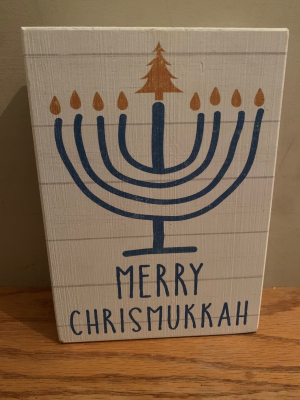 A small piece of artwork depicting a Hanukkah menorah with a Christmas tree as one of the candle flames reads, "Merry Chrismukkah."