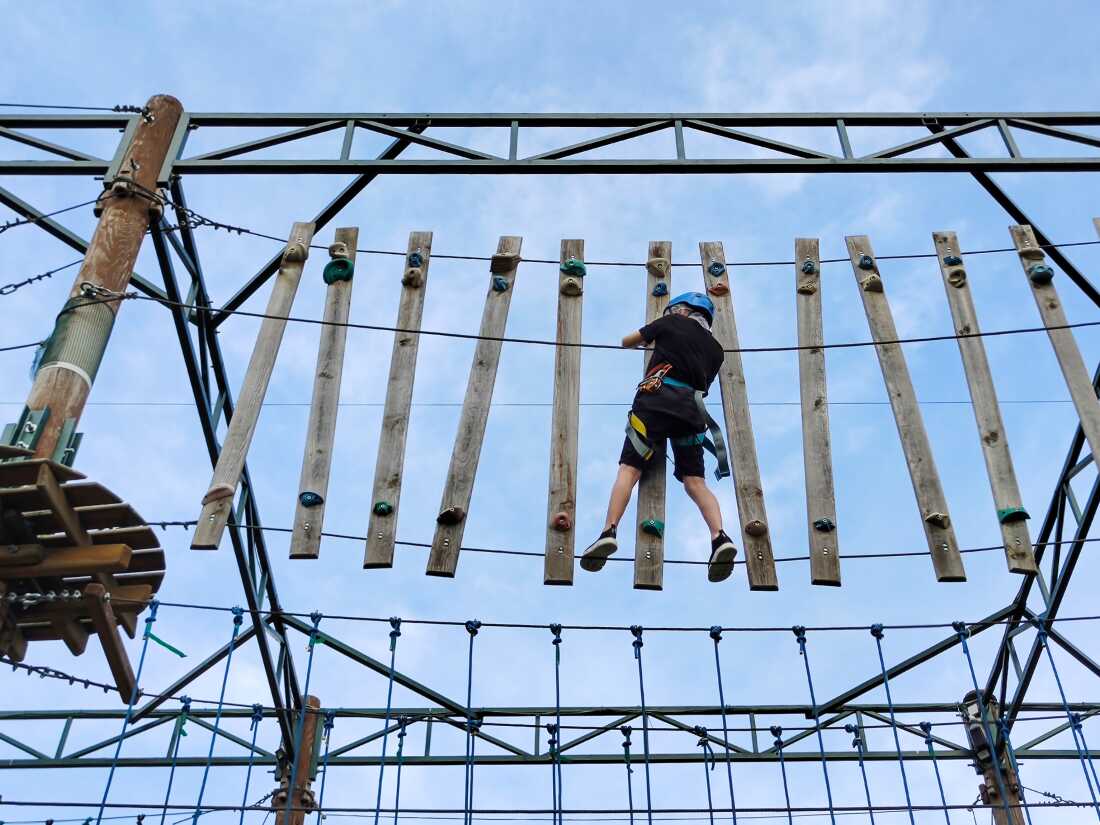 Un niño trepar un puente de cuerda colgante