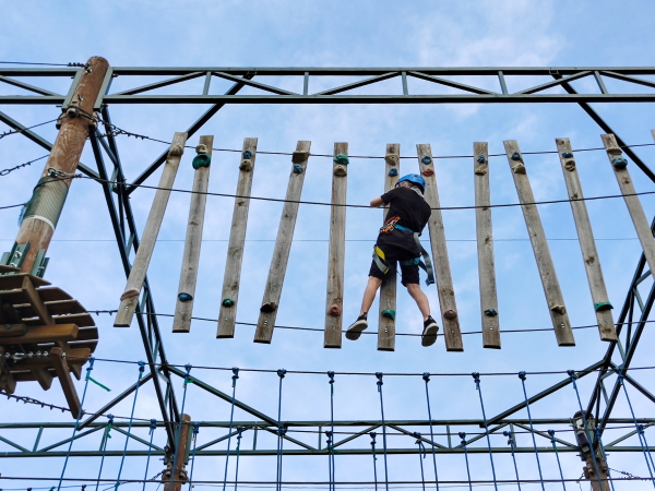A kid climbing a suspension rope bridge