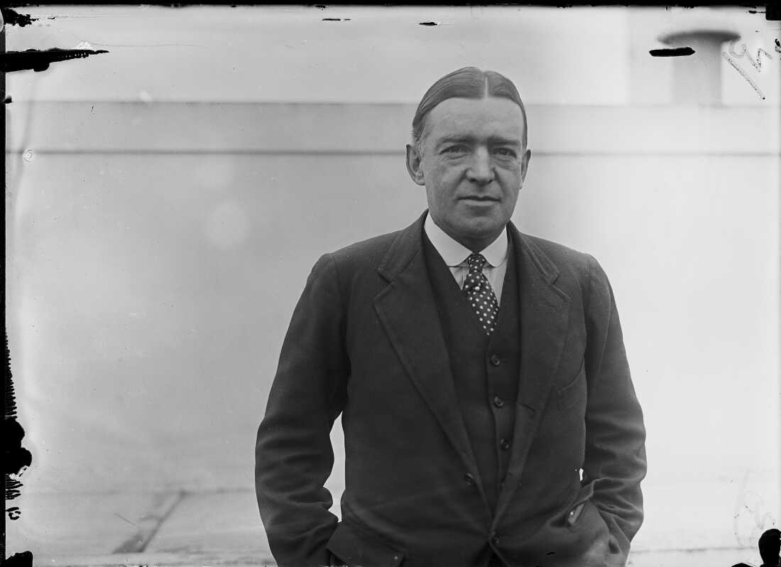 在這張黑白照片中,Polar Explorer Ernest Shackleton於1921年在紐約被描繪,從腰部周圍拍攝,他穿著夾克,背心,襯衫和領帶,他的頭髮在中間分開。