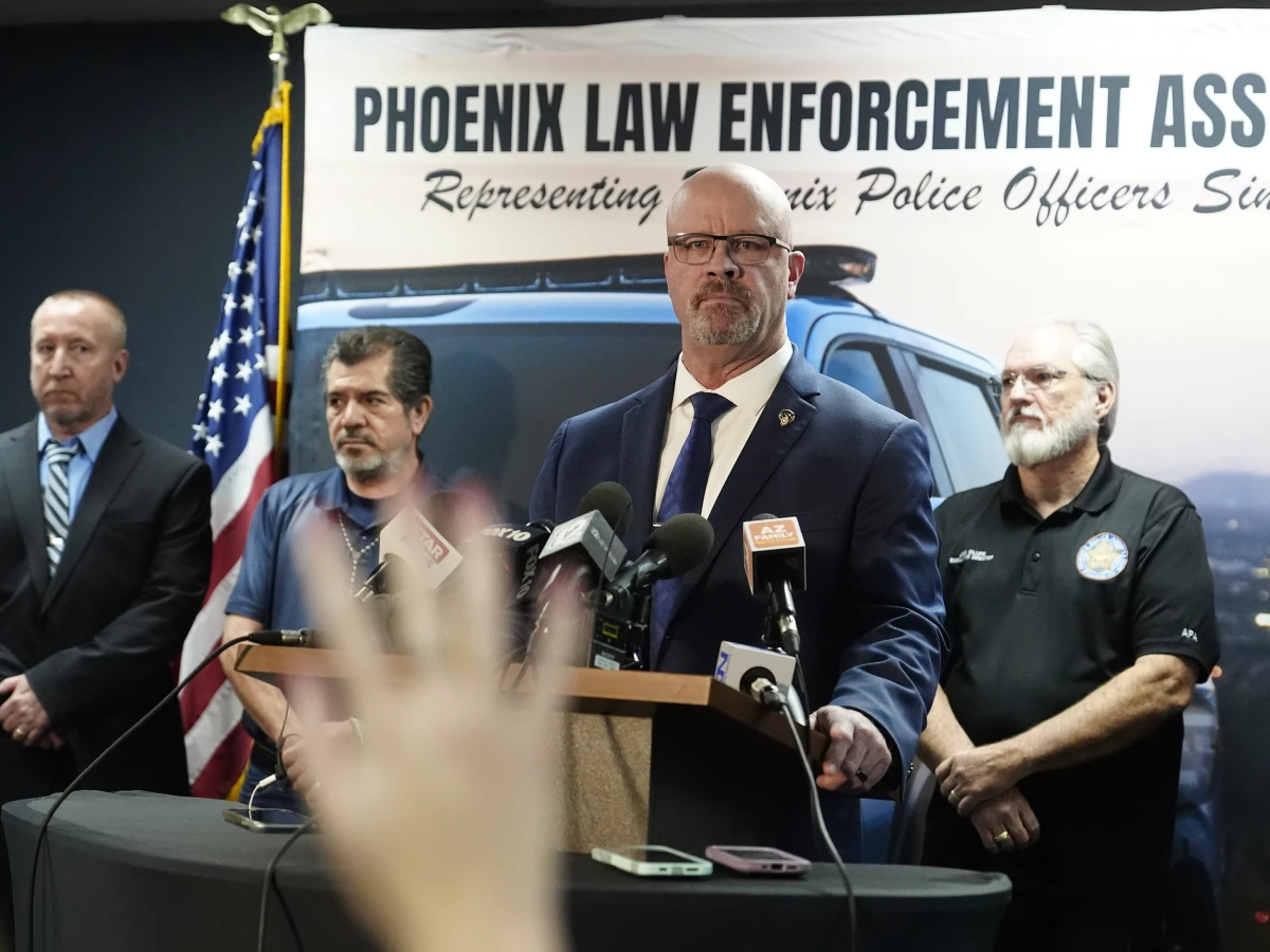 Darrell Kriplean, president of the Phoenix Law Enforcement Association, which represents about 2,200 Phoenix officers, stands at a lectern with microphones to take a question during a news conference Thursday in Phoenix. A Justice Department report said Phoenix police discriminate against Black, Hispanic and Native American people, unlawfully detain homeless people and use excessive force, including unjustified deadly force.