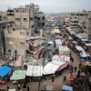 People walk past stalls selling goods amid the rubble of buildings destroyed during previous Israeli strikes, in Khan Yunis in the southern Gaza Strip on January 15, 2025.
