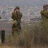 Israeli soldiers uses binoculars to look at damaged buildings in the Gaza Strip, from southern Israel, Wednesday, Aug. 13, 2025.
