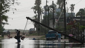 A man carries items through floodwater past downed electric lines after the passing of Hurricane Polo in Puerto San Carlos, Baja California Sur state, Mexico, Tuesday, Sept. 29, 2026.
