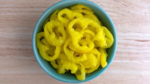 Sliced, yellow pickled banana peppers are shown in a blue bowl.