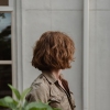 Dana is photographed with her red, chin-length hair obscuring her face, which is turned to the side.