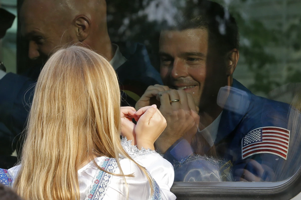 Reid Wiseman exchanges heart gestures with one of his daughters from a bus before his crew's rocket launched from Kazakhstan in May 2014. He went on to spend 165 days at the International Space Station.