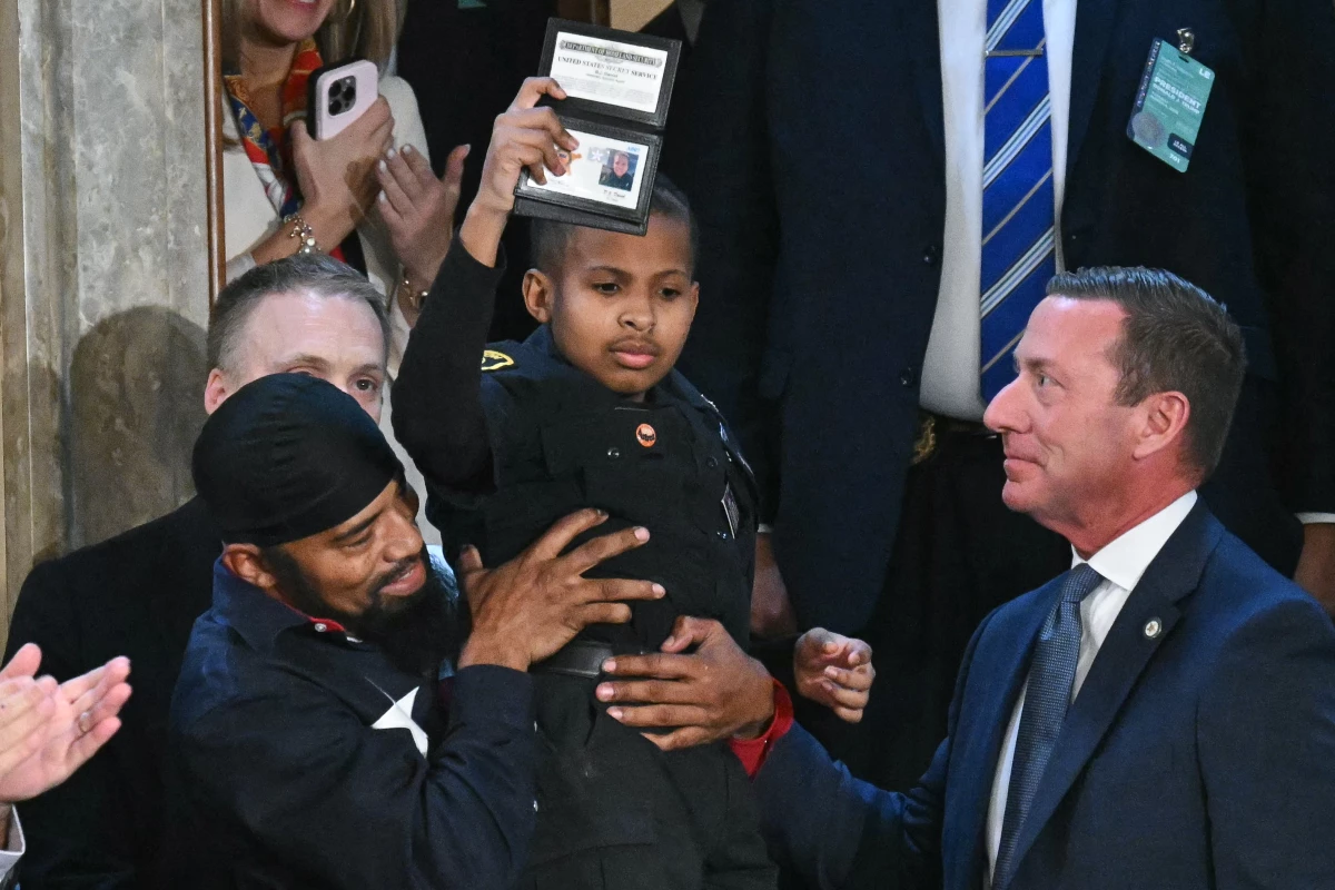 13-year-old cancer survivor Devarjaye 'DJ' Daniel is lifted up by his father Theodis Daniel after President Trump made him an honorary member of the US Secret Service during his address to a joint session of Congress.