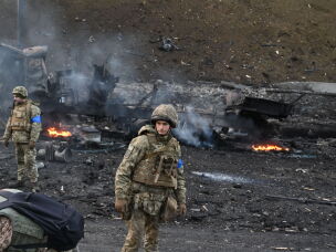 Ukrainian service members look for and collect unexploded shells after fighting against a Russian raiding group in Kyiv on Feb. 26, 2022.