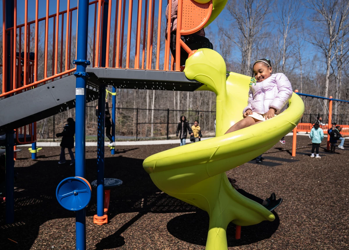 Aura goes down a spiral slide during recess.