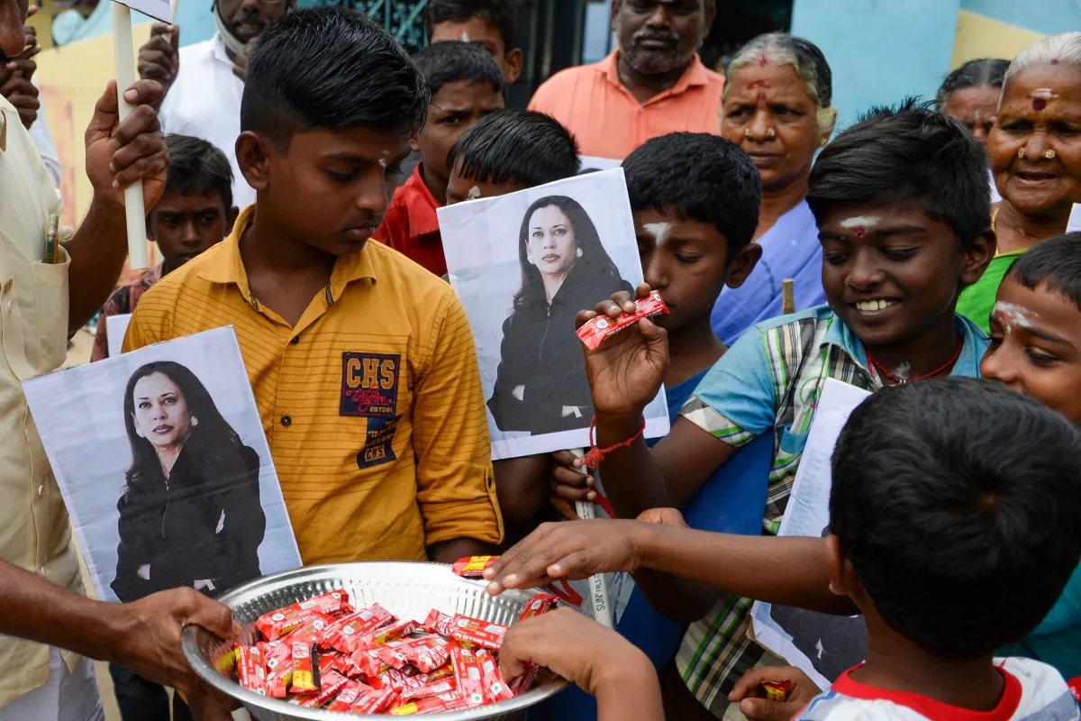 Villagers holding photos of Kamala Harris distribute sweets to celebrate Harris' inauguration as U.S. vice president in January 2021, in Harris' ancestral village of Thulasendrapuram.