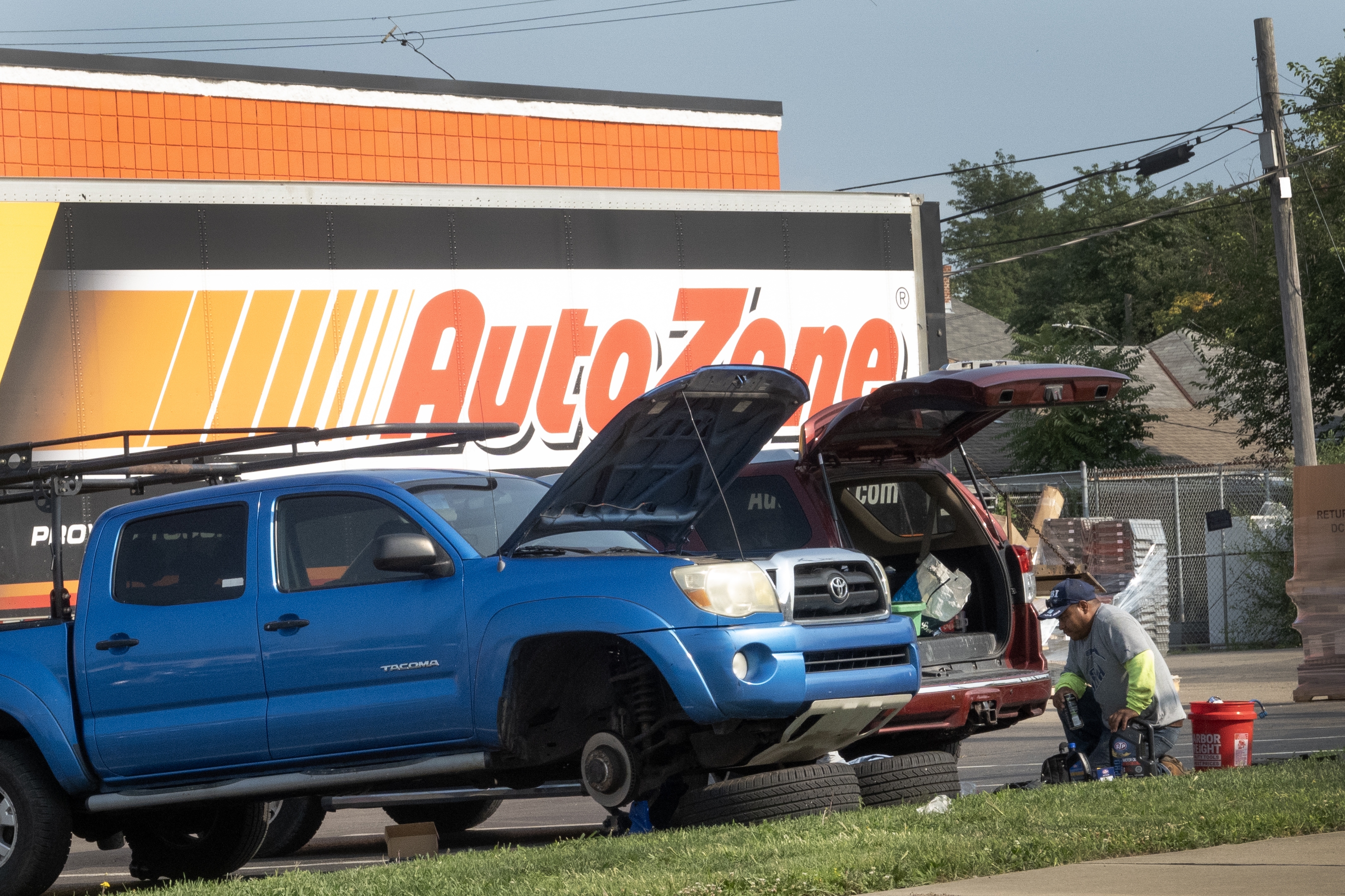 Men repair the brakes on a truck in the parking lot of an auto parts store in Middletown, Ohio, in 2024. Prices of car parts, car repairs and car insurance are expected to rise if tariffs remain in place.
