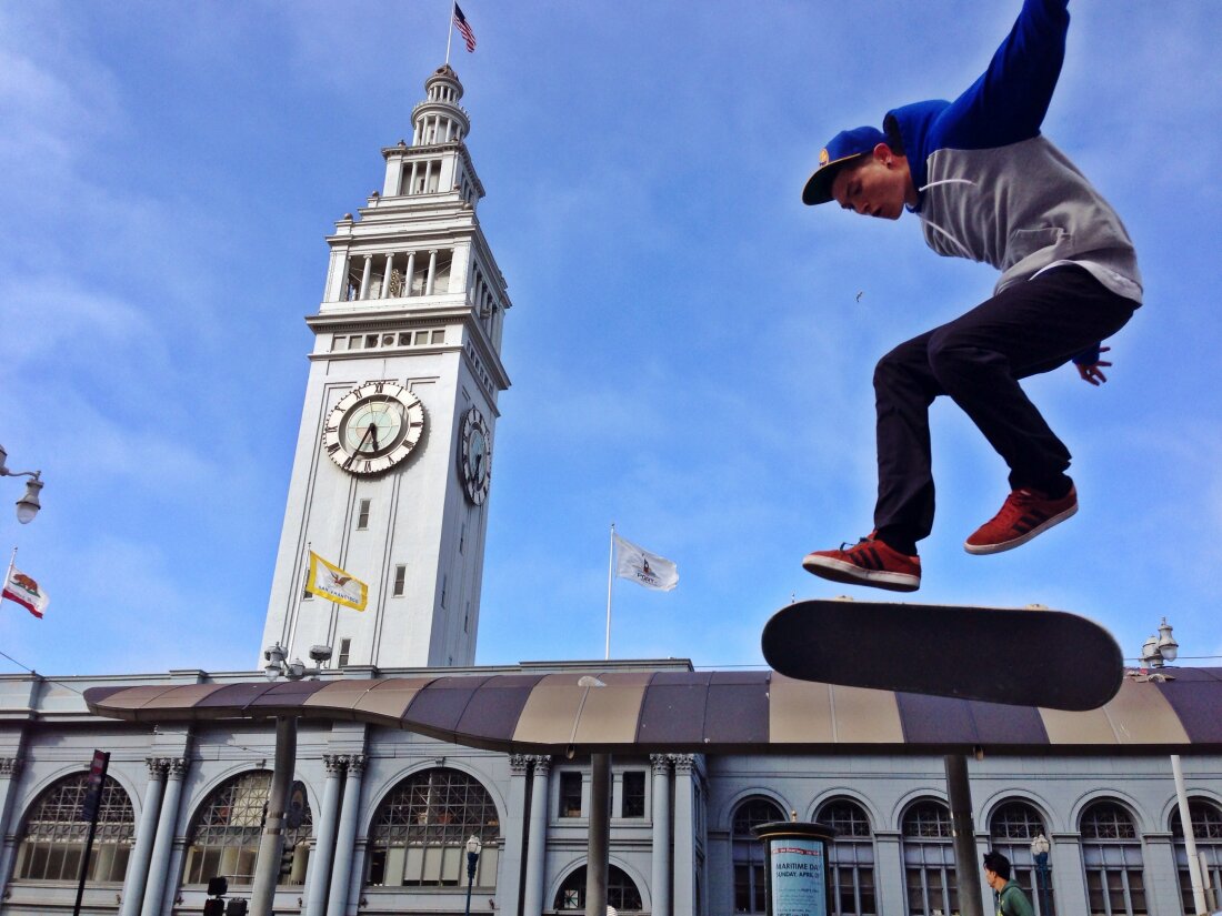 A young skateboarder riding in front of the Ferry Building on the Embarcadero in San Francisco California.