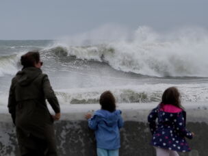 Spectators watch wave break during a nor'easter storm on Saturday in Hampton, N.H.