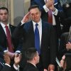 Elon Musk stands as he is recognized by President Trump during the latter's address to a joint session of Congress on Tuesday. Musk is holding his hand at his forehead in a salute gesture, and he's wearing a blue suit with a blue tie. He's surrounded by other attendees of the address, who are applauding.