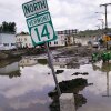 A small tractor clears water from a business as flood waters block a street, July 12, 2023, in Barre, Vt. Vermont has become the first state to enact a law requiring fossil fuel companies to pay a share of the damage caused by climate change, Thursday, May 30, 2024, after the state suffered catastrophic summer flooding and damage from other extreme weather.