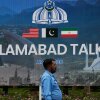 A police officer walks past a billboard regarding the United States and Iran negotiations, outside a media facilitation center in Islamabad, Pakistan, Saturday, April 11, 2026.