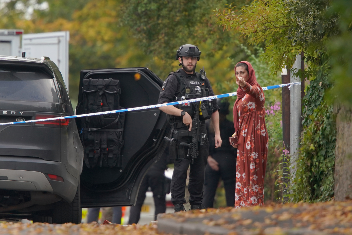 An armed police officer speaks to member of the public near the scene of a stabbing incident at Heaton Park Hebrew Congregation synagogue, in Crumpsall, Manchester, England, Thursday, Oct. 2, 2025.